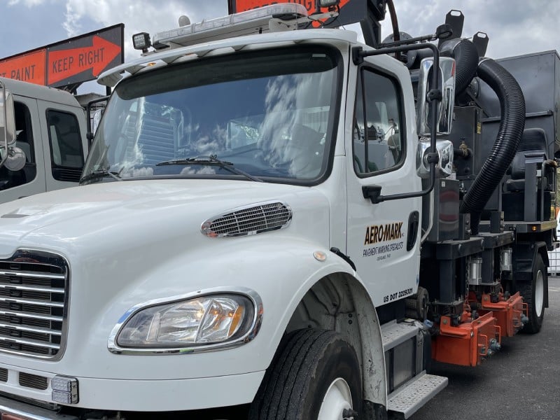 White utility truck with road maintenance equipment and “Aero-Mark”