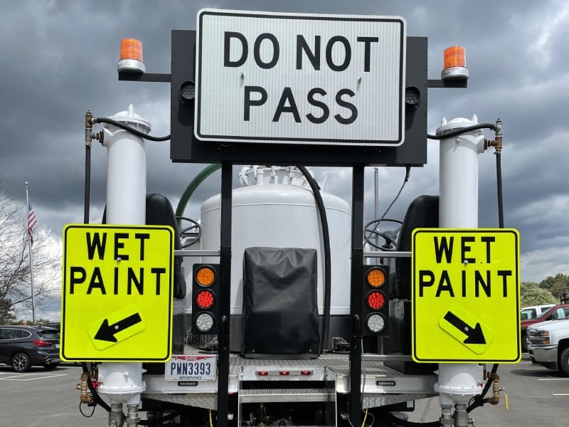 Road marking vehicle with "DO NOT PASS" and "WET PAINT" signs